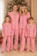 Family standing by a Christmas tree in red and white vertical-striped button-up pajamas with green trim.