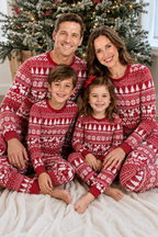 Family cuddling on a blanket by a Christmas tree in red pajamas with white Fair Isle reindeer and tree patterns.