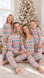 Family of four sitting in front of a decorated Christmas tree in matching reindeer and snowflake pajamas.