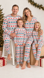 Family of four wearing matching white Christmas pajamas with red reindeer and green snowflakes beside holiday garlands.