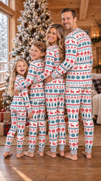 Family of four posing beside a Christmas tree in coordinating red, green and white long-sleeve pajama sets.