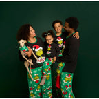 Family wearing black Grinch tops and green printed pajama pants while holding a dog against a green backdrop