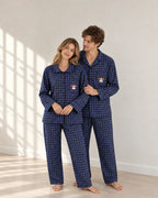 Standing portrait of a couple in blue plaid pajamas, showing the woman's rounded collar, man's notched collar and dog embroidery with red glasses.
