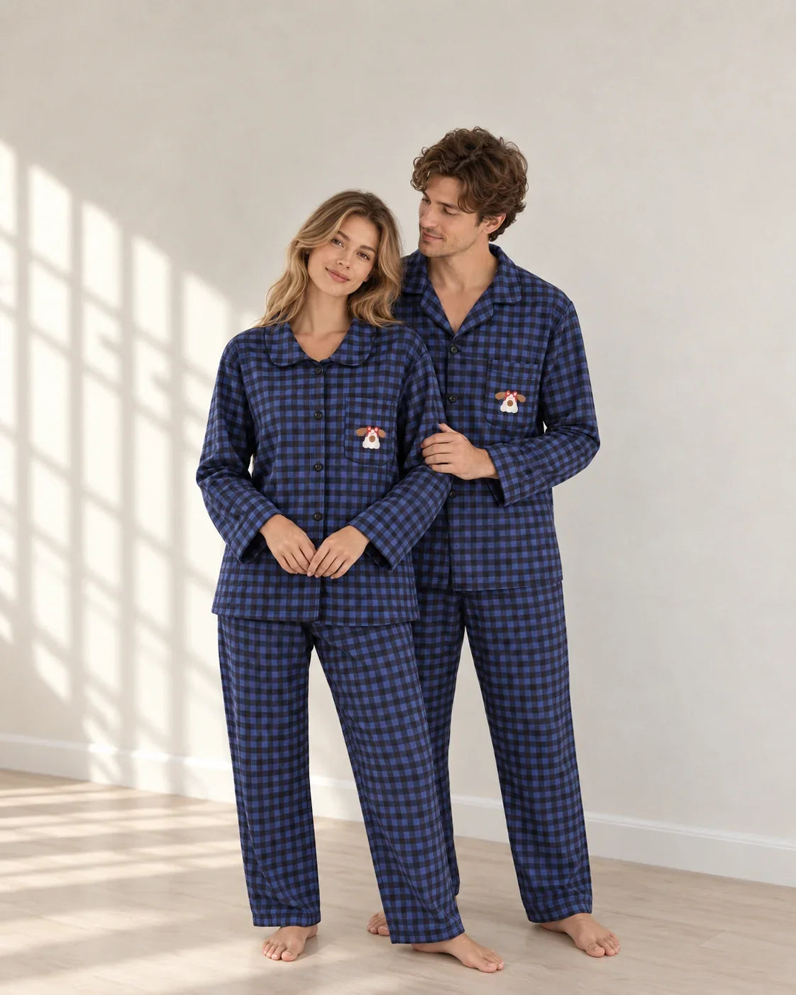 Standing portrait of a couple in blue plaid pajamas, showing the woman's rounded collar, man's notched collar and dog embroidery with red glasses.