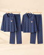 Matching women's and men's blue plaid pajama sets with dog embroidery