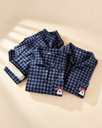 Folded blue plaid pajama sets showing dog embroidery and fleece interior