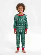Young boy with curly hair wearing green Fair Isle Christmas pajamas with white trees, snowflakes and red cuffs.