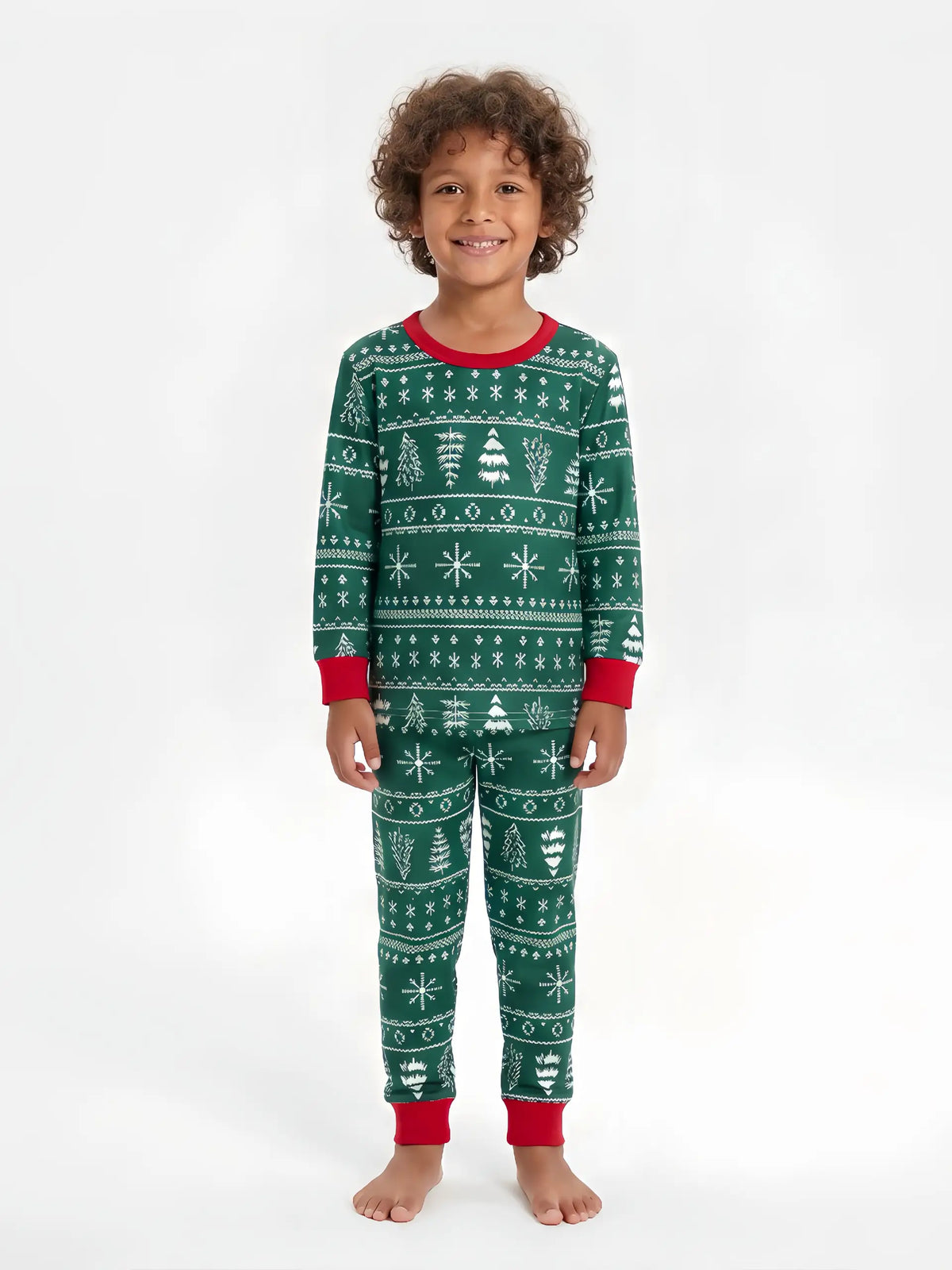 Young boy with curly hair wearing green Fair Isle Christmas pajamas with white trees, snowflakes and red cuffs.