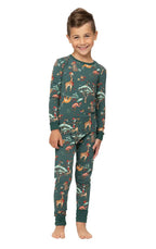 Smiling young boy standing in a two-piece dark green matching family Christmas pajama set with holiday animal design.