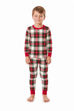 Boy wearing red, white and black plaid Christmas pajamas with red neckline, wrist and ankle trim.