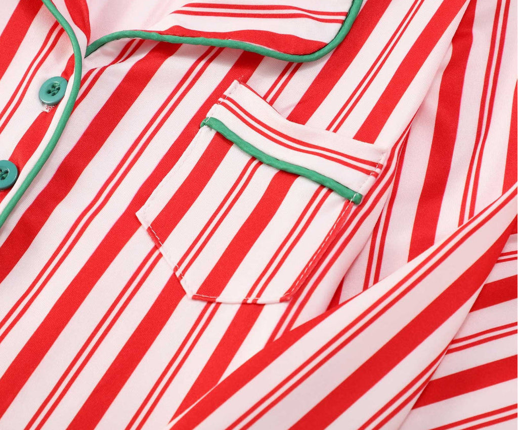 Close-up detail of a red and white candy cane striped pajama top featuring green contrast piping trim, a notch lapel collar, and a chest pocket.