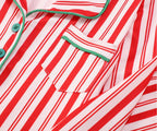 Close-up detail of a red and white candy cane striped pajama top featuring green contrast piping trim, a notch lapel collar, and a chest pocket.