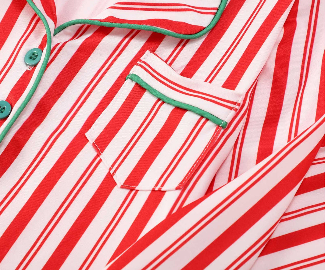 Close-up detail of a red and white candy cane striped pajama top featuring green contrast piping trim, a notch lapel collar, and a chest pocket.
