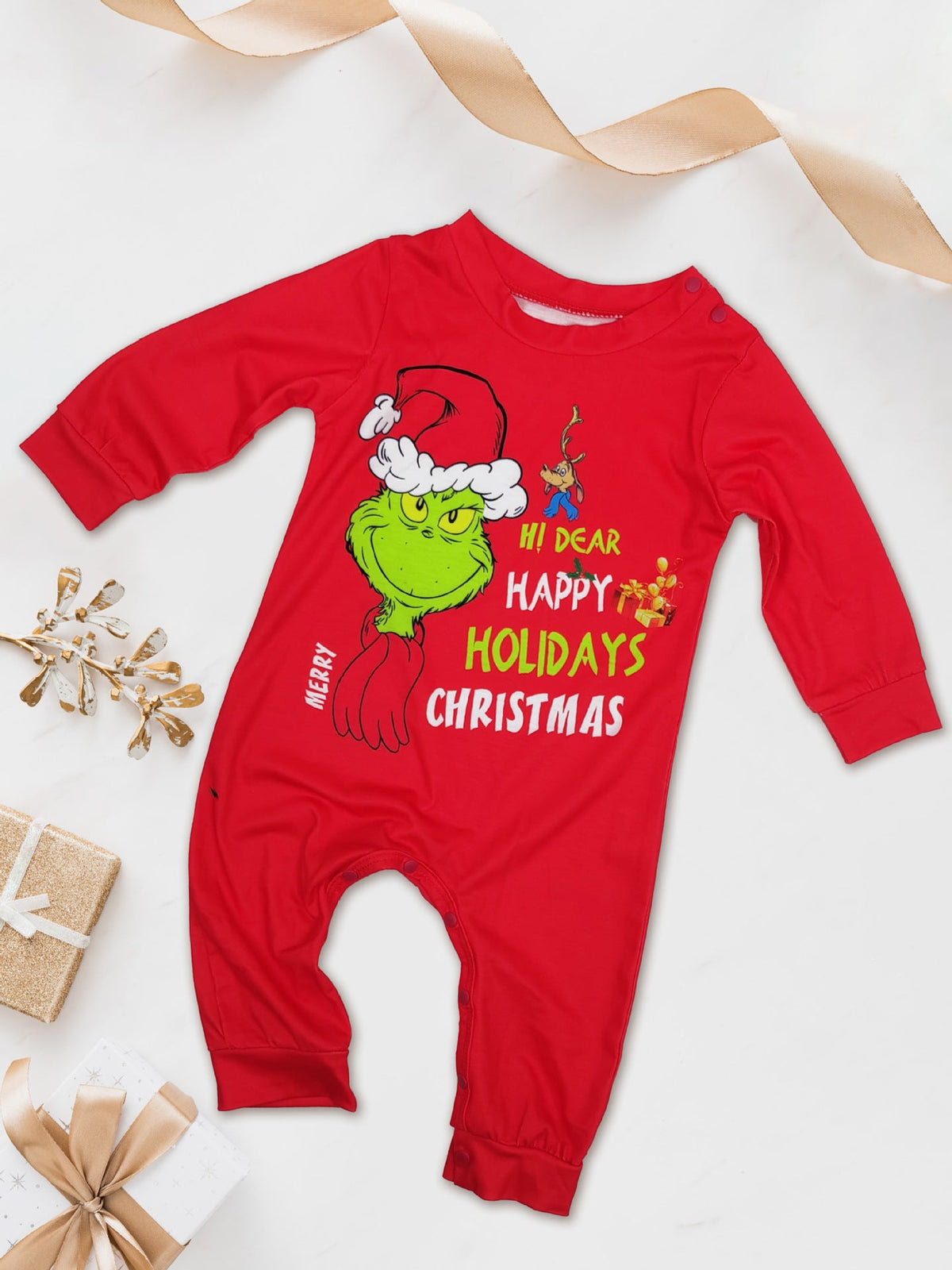 Red long-sleeve baby romper with a Grinch face and festive lettering beside wrapped gifts