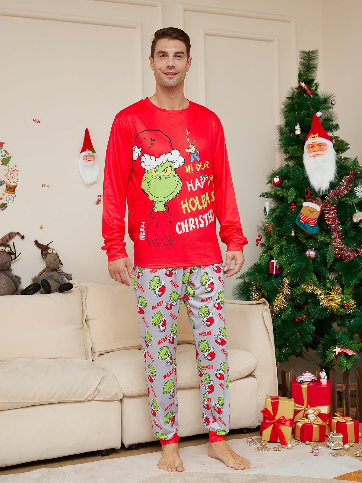 Man wearing a red Grinch Christmas top and light gray character-print pajama pants