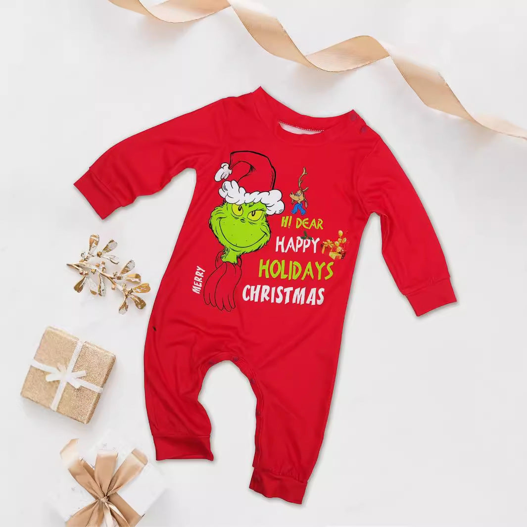 Red baby romper with a Grinch Santa-hat graphic and festive lettering, displayed beside wrapped gifts