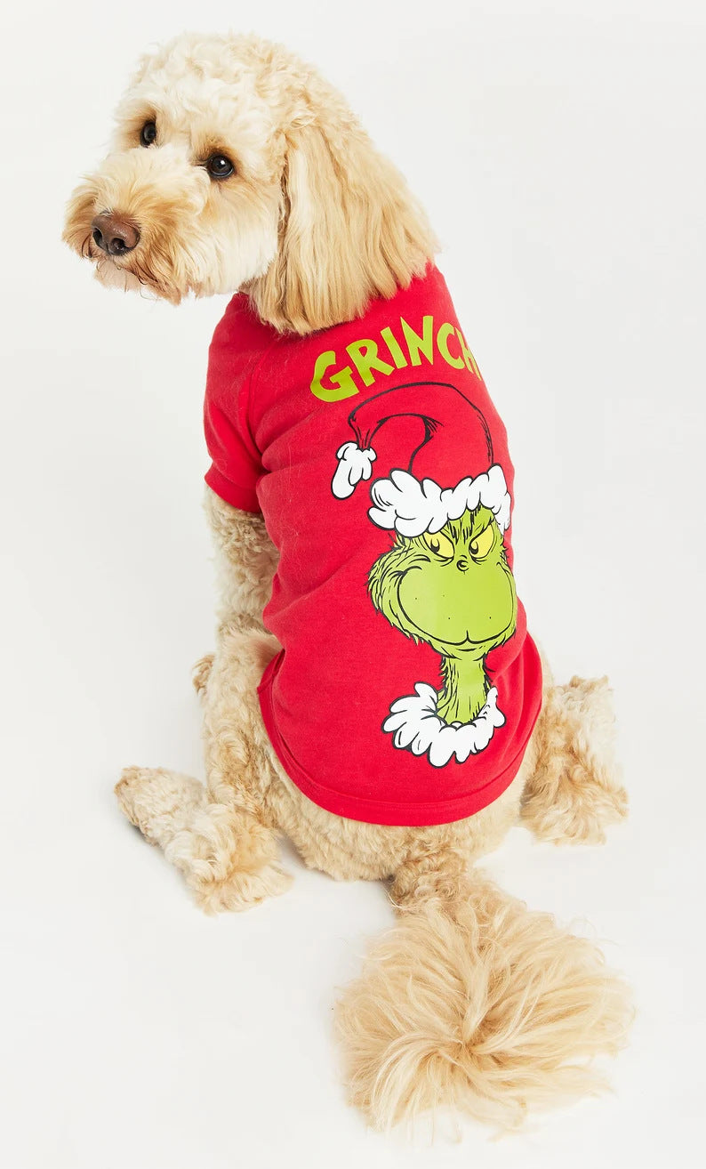 Small dog wearing a red Christmas shirt with a Grinch face and yellow lettering