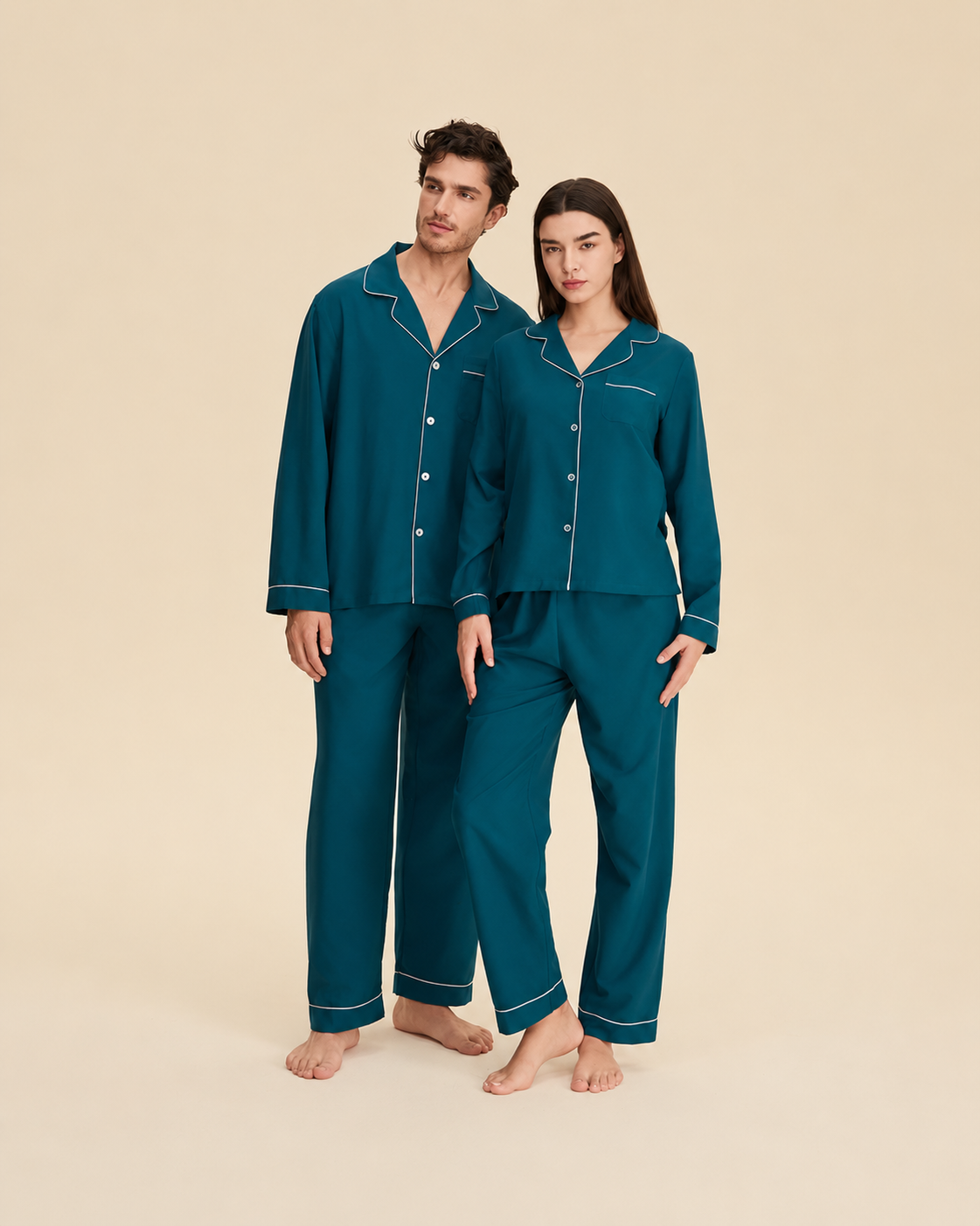 Couple wearing teal blue long-sleeve button-front pajamas with contrast piping and matching long pants.