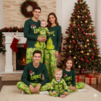 Family wearing dark green Grinch tops and lime-green printed Christmas pajama pants beside a fireplace
