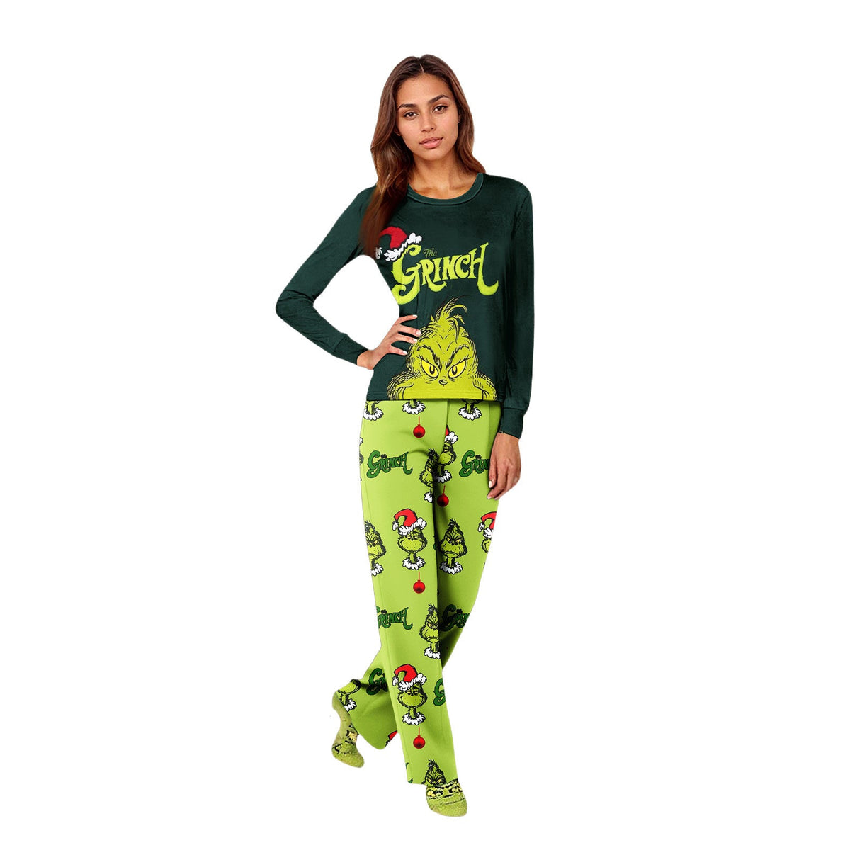 Woman standing in a dark green Grinch top and lime-green character-print pajama pants