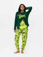 Woman posing with raised arms in a dark green Grinch top and lime-green printed pajama pants