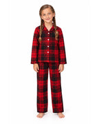 Girl wearing a red and black plaid pajama shirt and long pants on a white background.