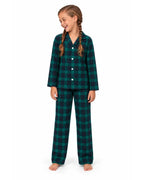 Girl wearing a green and black plaid pajama shirt and long pants on a white background.