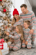 Family decorating a Christmas tree in grey pajamas patterned with rows of red reindeer and green trees.