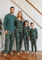 Family beside a staircase in teal animal-print pajamas, with dad in a solid Henley and matching printed pants.