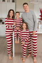 Parents and two children posing in a kitchen in red and white striped pajamas, with dad in a grey Henley.