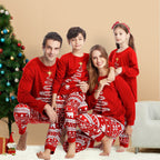 Family of four sitting by a decorated Christmas tree in matching red holiday pajamas featuring white brush-stroke Christmas tree tops with yellow stars and Nordic Fair Isle polar bear print pants.
