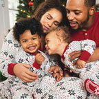 Happy family hugging in matching white snowflake Fair Isle Christmas pajamas and a red Henley shirt.