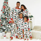 Happy family of four wearing matching white Christmas sleepwear with vintage red trucks standing by a decorated tree.