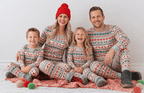 Family sitting on a red blanket in grey pajamas with red reindeer and green snowflakes, surrounded by yarn balls.