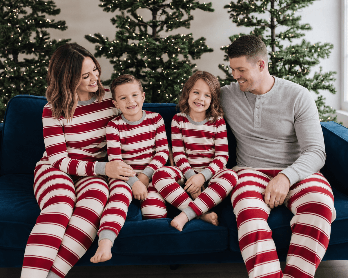 Family sitting on a blue sofa in red and white striped Christmas pajamas, with dad in a grey Henley.