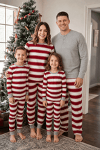 Family standing beside a Christmas tree in red and white striped pajamas, with dad in a grey Henley.