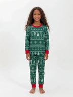 Girl wearing green Christmas pajamas with white snowflake and tree patterns, a red neckline and red cuffs.