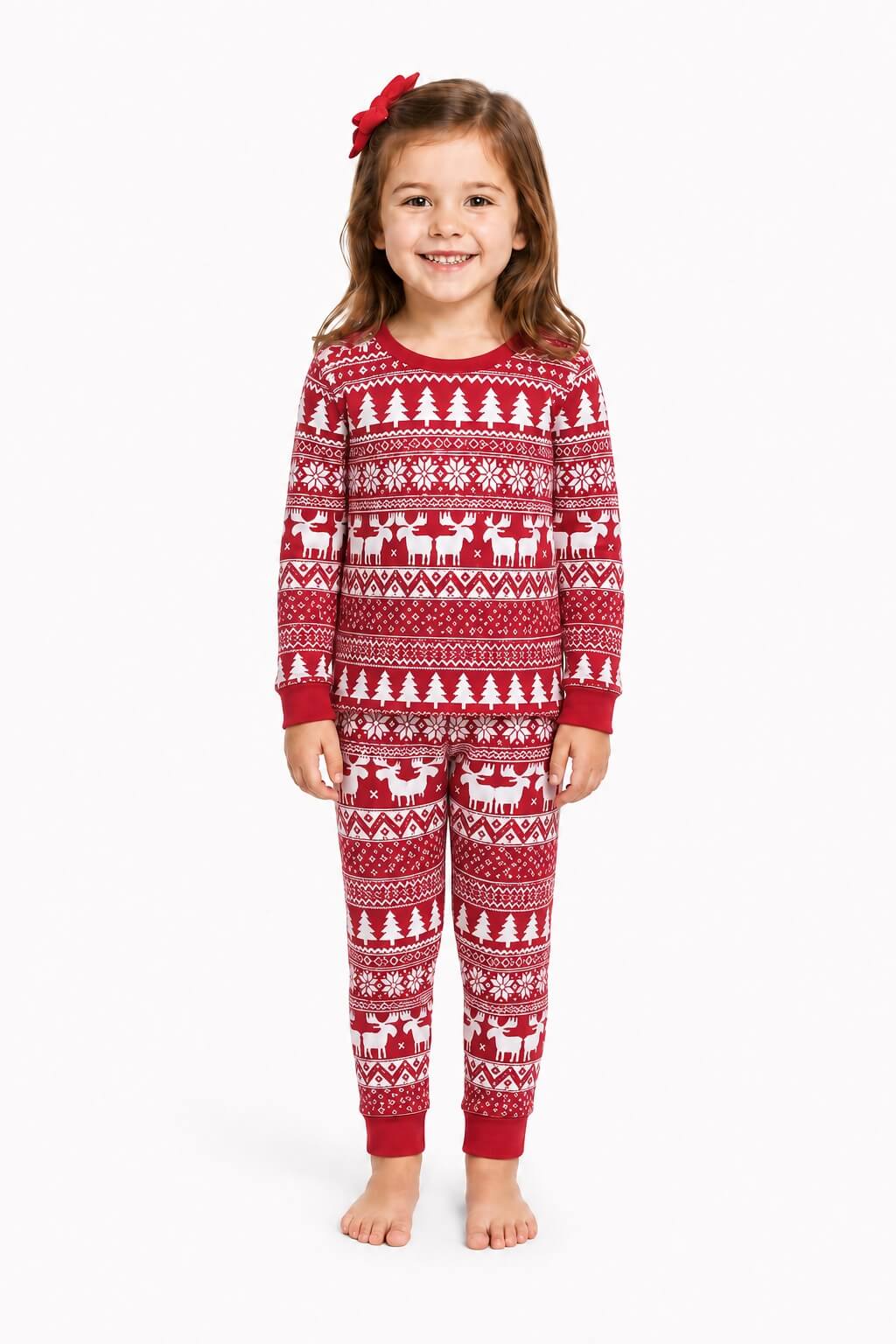 Girl wearing red Christmas pajamas with white tree and reindeer patterns, red cuffs and a red hair bow.