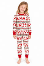 Girl wearing white Christmas pajamas with red reindeer, snowflakes and red cuffs against a white background.