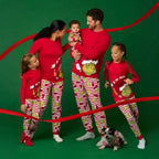 Family in red Grinch tops and red-and-white striped Christmas pajama pants with a baby and dog