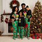 Family in black Grinch tops and green printed Christmas pajama pants beside a decorated tree with their dog