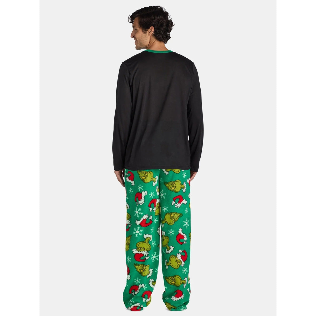 Rear view of a man in a plain black pajama top and green pants with Grinch faces and Santa hats