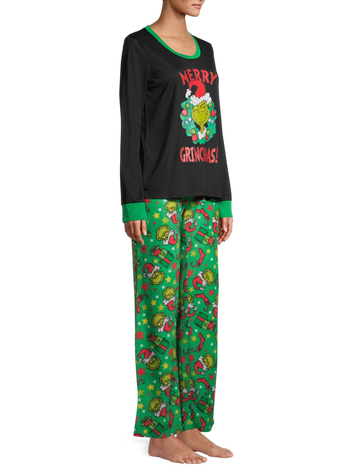 Side view of a woman wearing a black Grinch wreath top and green Christmas pajama pants