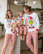 Matching Grinch family Christmas pajamas with white long-sleeve tops and colorful striped pants.