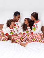 Parents and children relaxing on a bed in matching Grinch Christmas pajamas.