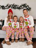 Family seated together in matching Grinch Christmas pajama sets.