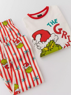 Close-up of the Grinch print on a white pajama top and matching striped pants.