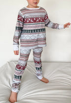 Young boy standing in kids grey Fair Isle patterned Christmas long-sleeve top and fitted pants.