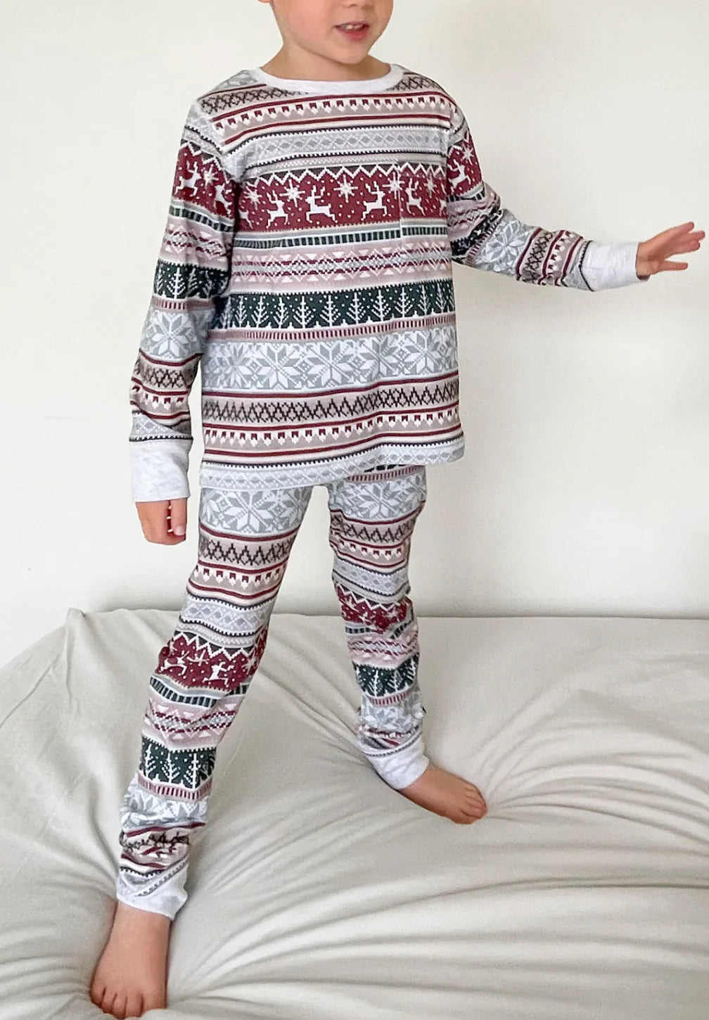 Young boy standing in kids grey Fair Isle patterned Christmas long-sleeve top and fitted pants.