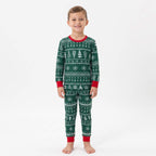 Boy modeling green Christmas pajamas with white Fair Isle tree and snowflake patterns and red cuffs.